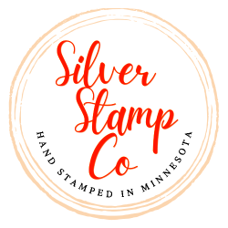 Silver Stamp Co logo, orange hand lettering in a rough circle