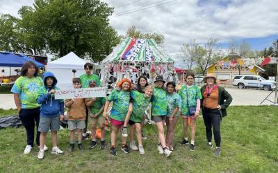 FSM students standing in front of the Zero Waste tent, holding a sign that says "Where did last year's waste go?". They are standing in front of a large sculplture of a jellyfish, made with recycled items from the sale.