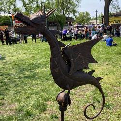 Rusted iron dragon sculpture perched on a small sphere