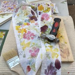 White fabric with impressions of colorful flowers next to a hammer. 